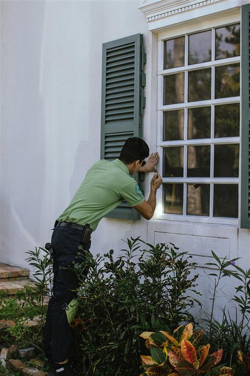 Certified home inspector examining a window frame on a residential property, ensuring thorough inspection for safety and functionality.