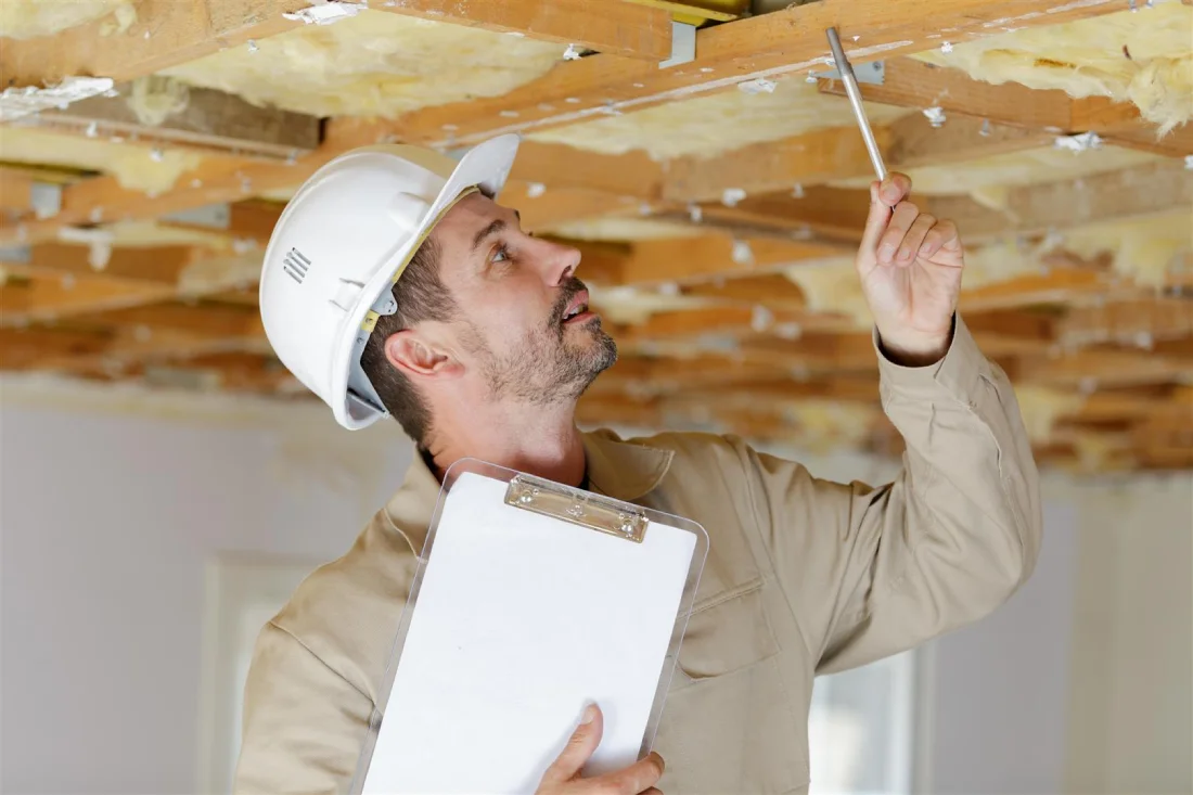 Home inspector examining ceiling insulation with a clipboard in hand, ensuring quality in a Miami property inspection.