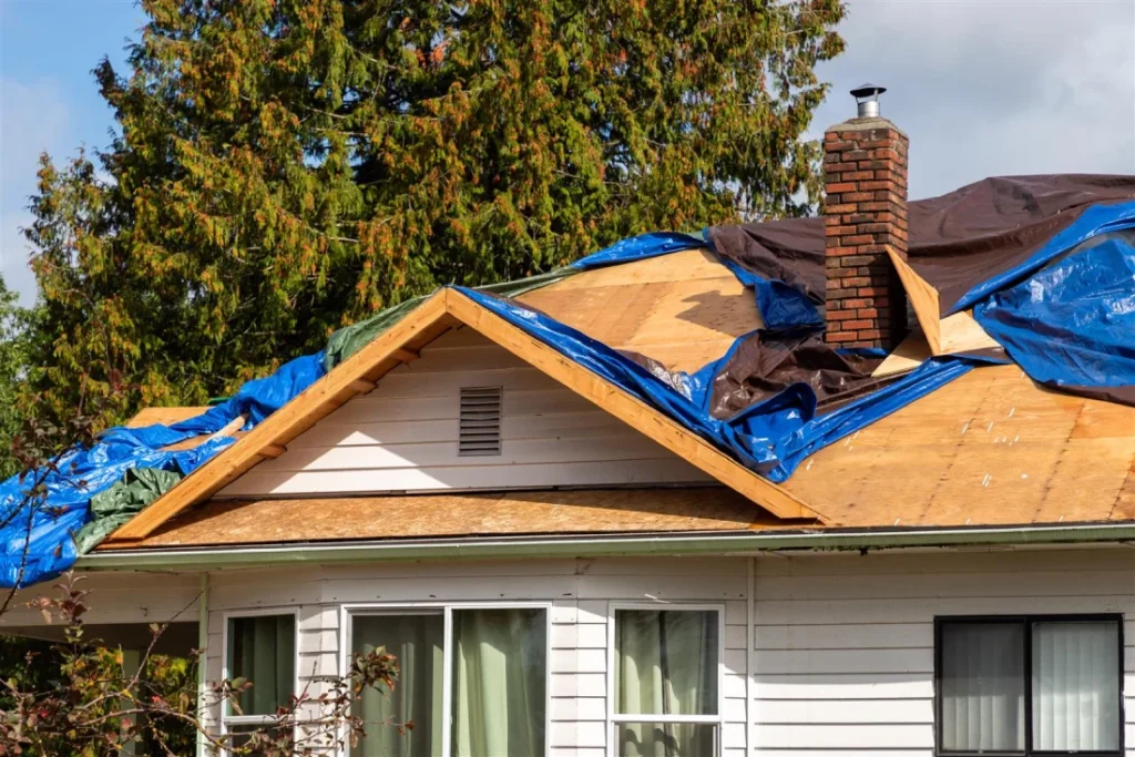 Home inspector documenting roof damage and temporary tarp installation during storm repair assessment