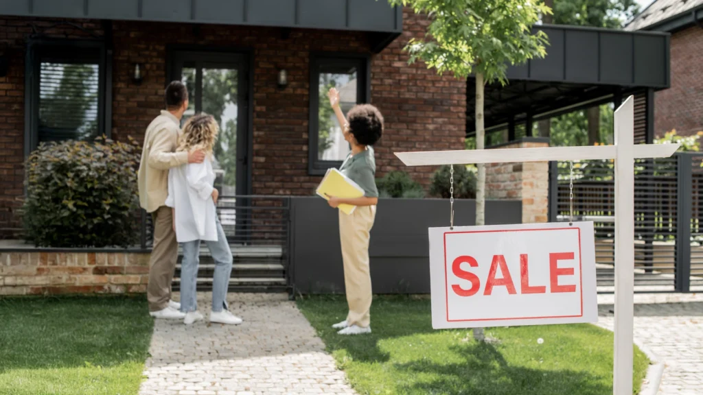 Home inspector showing a house for sale to a couple during a pre listing home inspection for sellers, with a visible “SALE” sign in front yard.